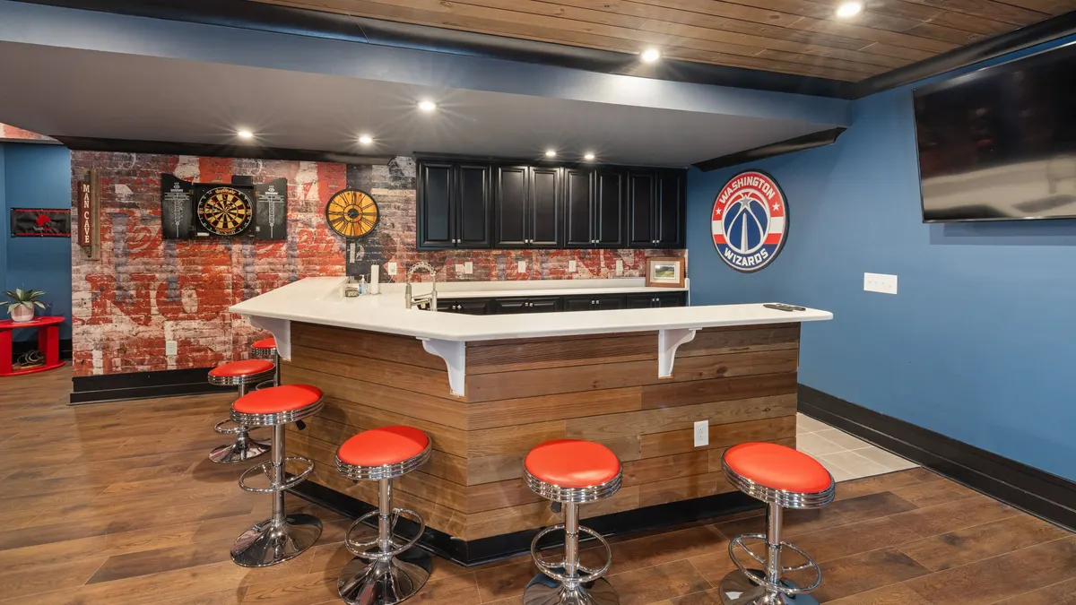 A stylish home bar with stools, bright decor and a wall-mounted screen