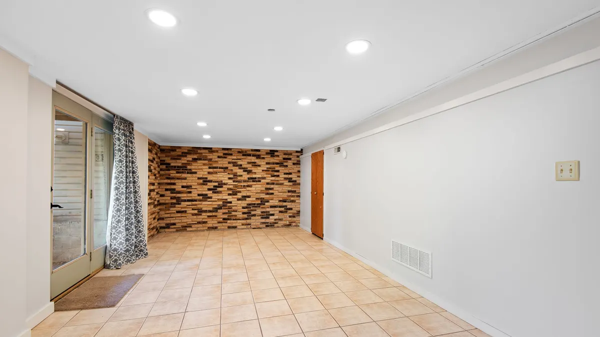 A finished basement room with tiled flooring and a feature wall