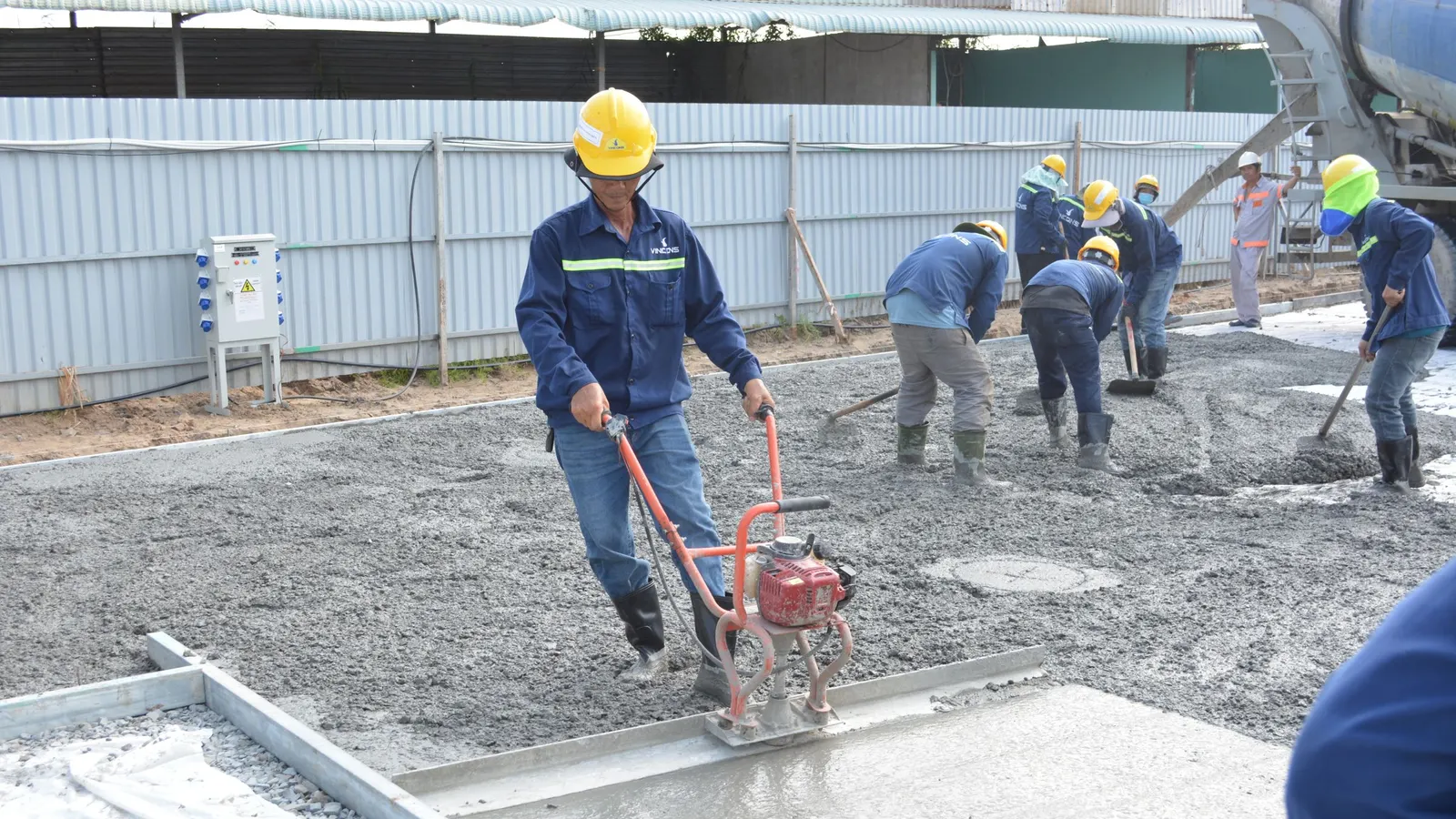 Workers finishing a freshly poured concrete slab with a power float