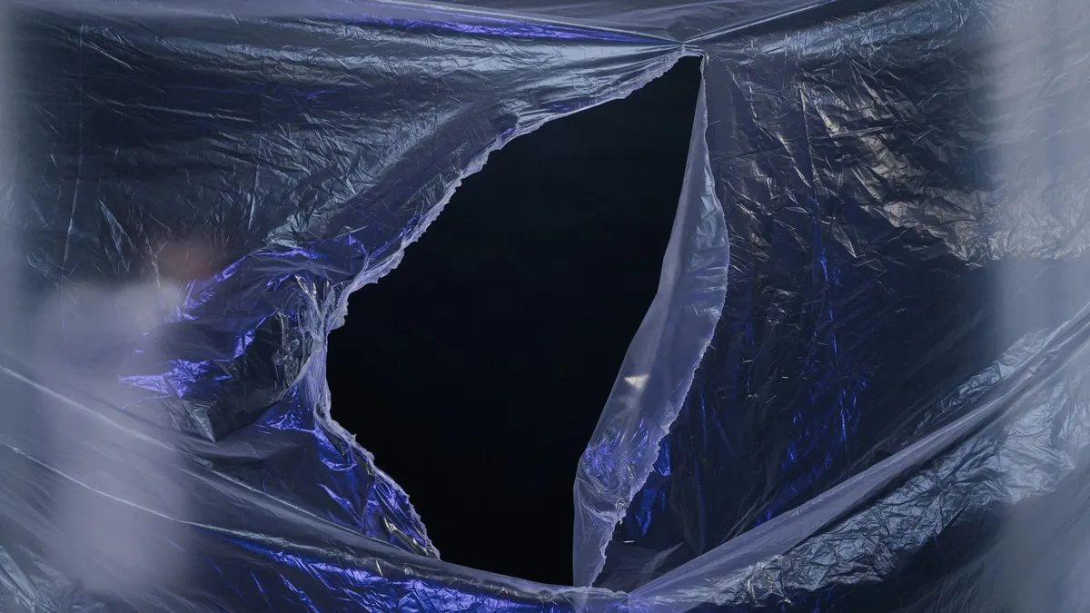 A torn sheet of translucent plastic with a dark gap behind it