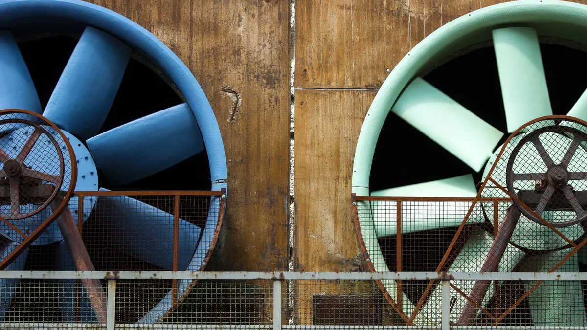 Large industrial ventilation fans mounted on an aging wall