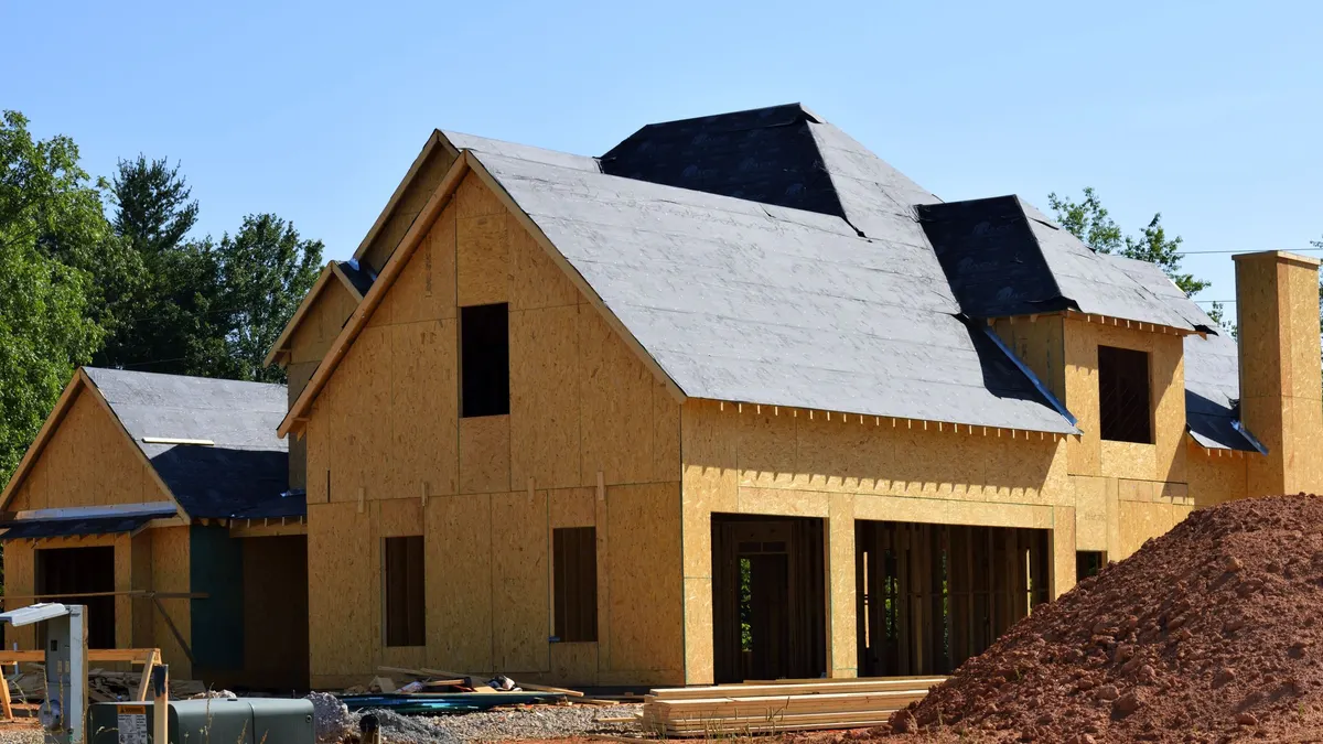 A timber-framed house under construction with sheathing in place