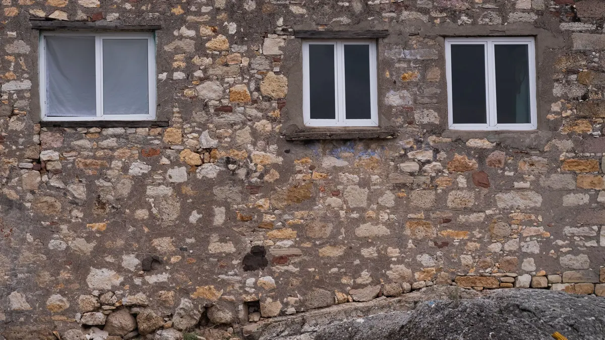Modern windows set into a weathered stone facade