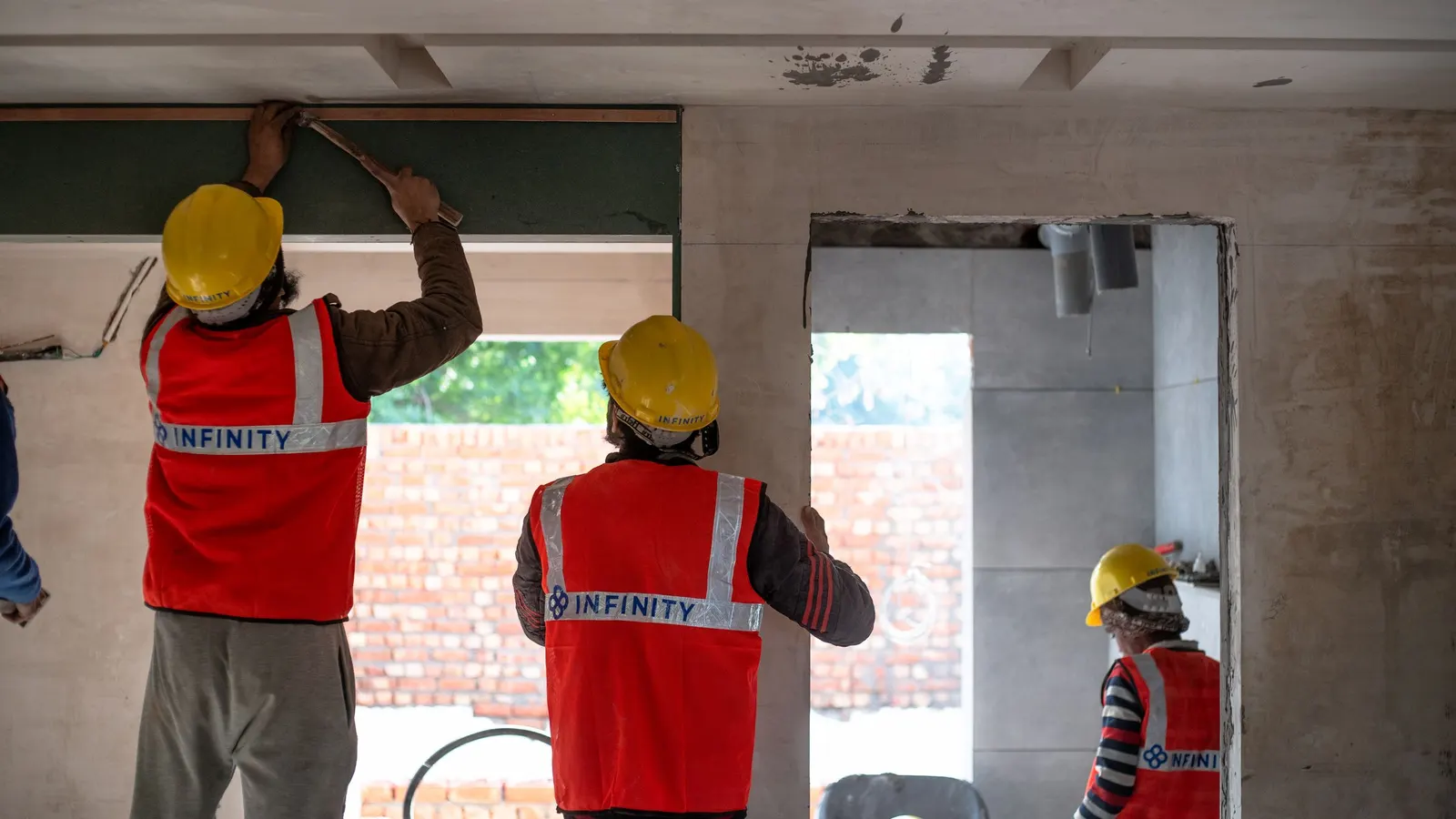 Construction workers in hard hats and high-visibility vests renovating an interior space