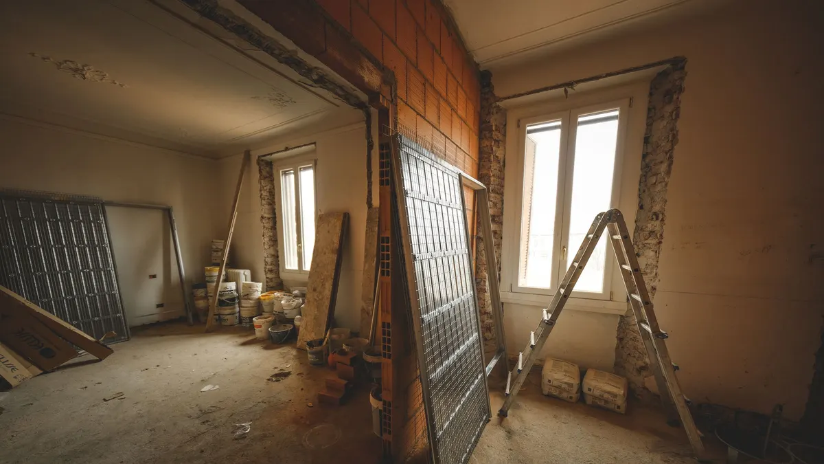 An interior under renovation with a window opening and a stepladder