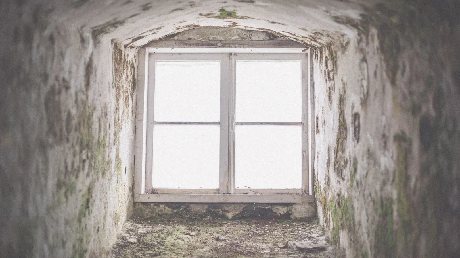 A bare window framed in the rough wall of a derelict building