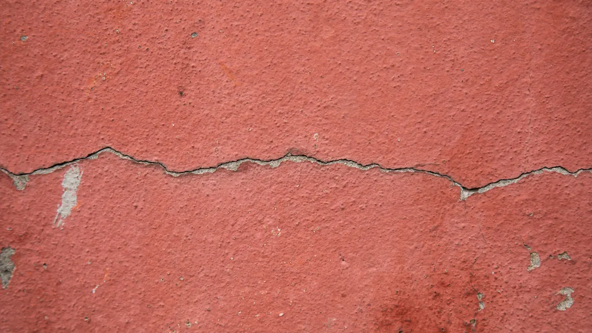 A long horizontal crack running across a painted rendered wall