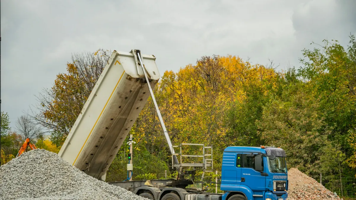 A tipper truck discharging a load of crushed stone at a site
