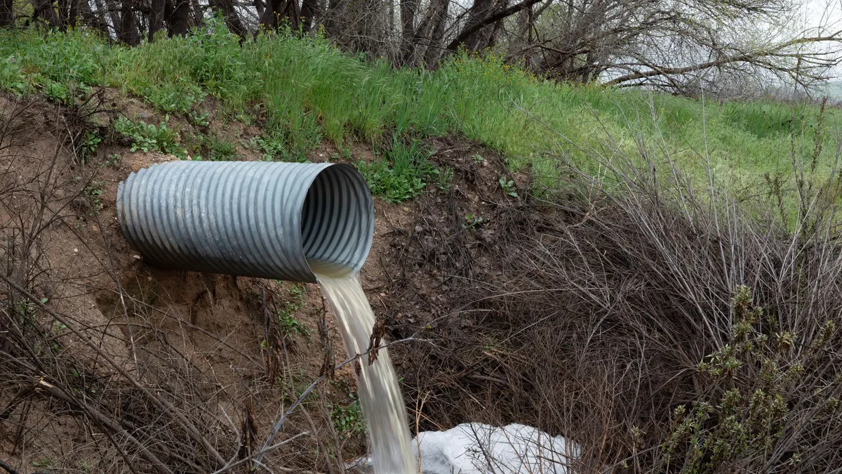 A corrugated drainage pipe discharging water into a ditch