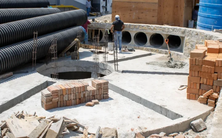 Coiled corrugated drainage pipe stacked beside bricks on a building site
