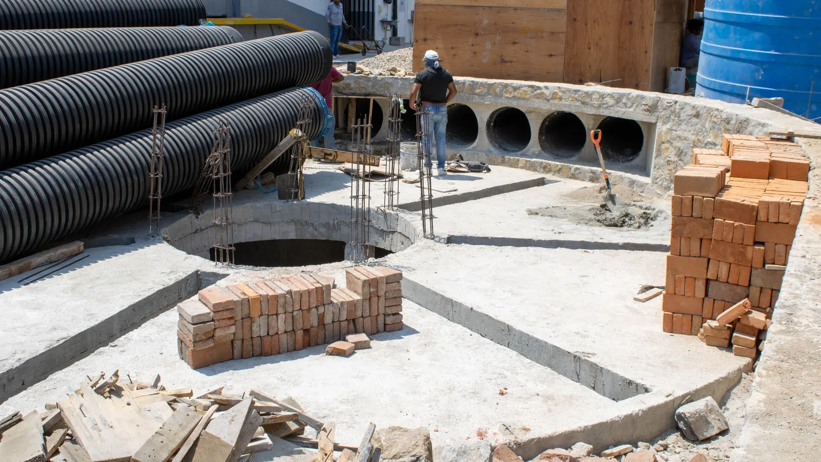 Coiled corrugated drainage pipe stacked beside bricks on a building site