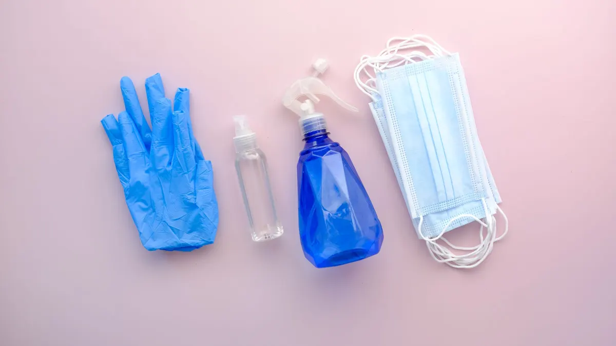 Protective gear laid out flat: gloves, sanitiser and a face mask
