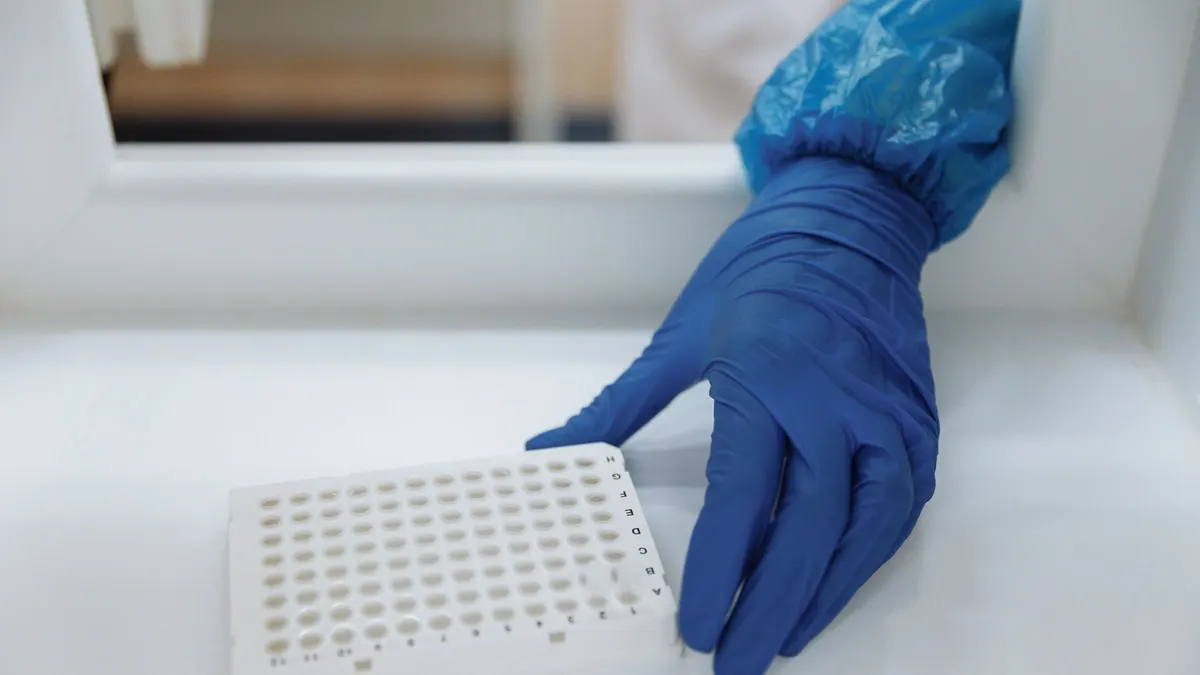A scientist in protective gloves handling test samples in a laboratory