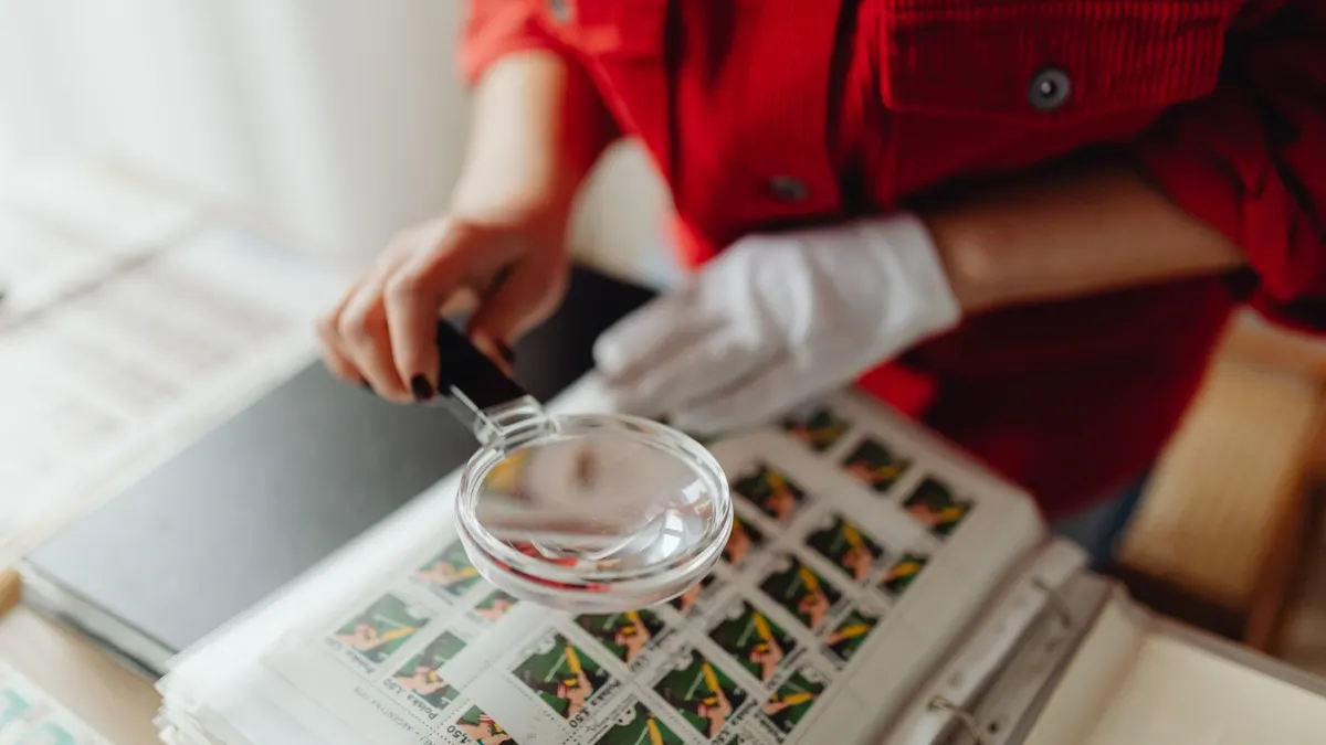A person examining small printed items closely with a magnifying glass