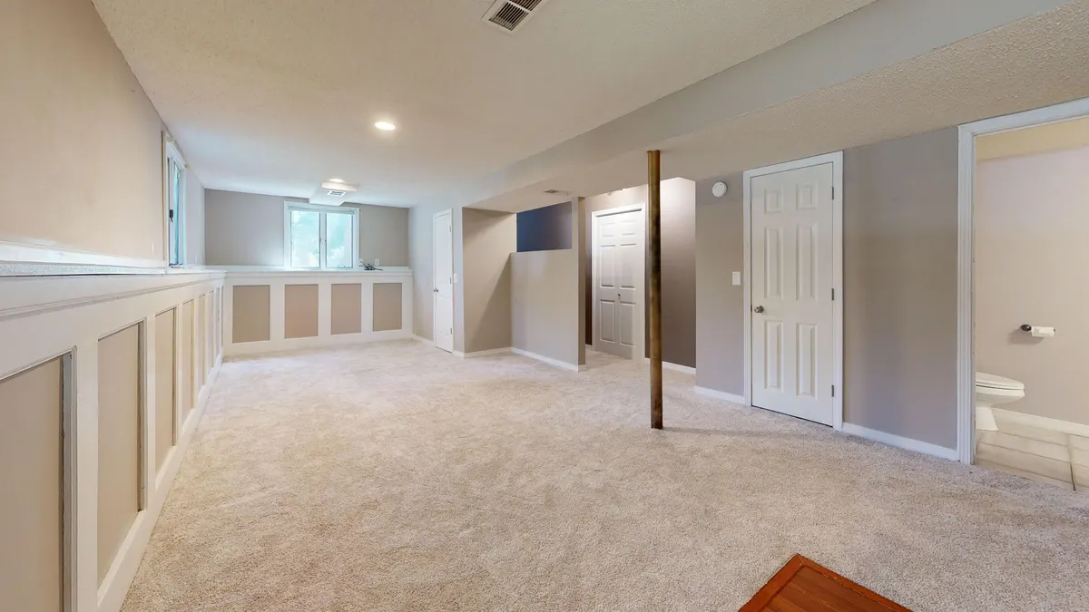 An unfinished basement interior with framed walls and carpet