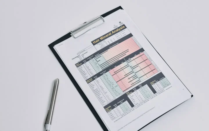 A printed report with a coloured results table on a clipboard beside a pen