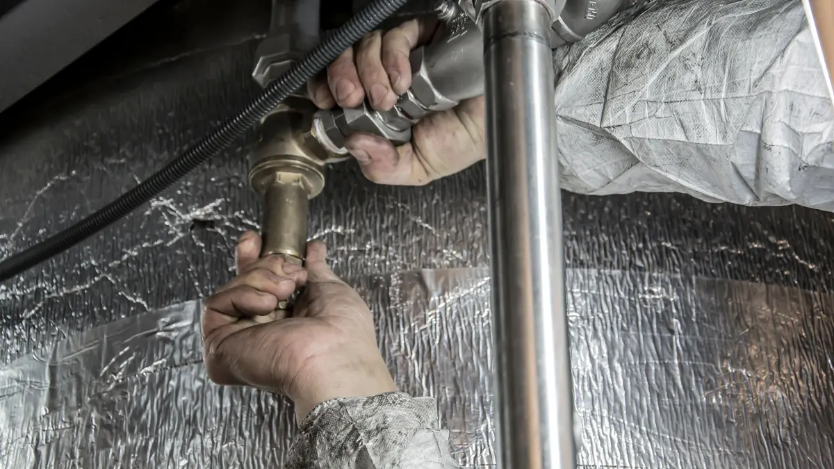 A person's hands working on a metal pipe fitting