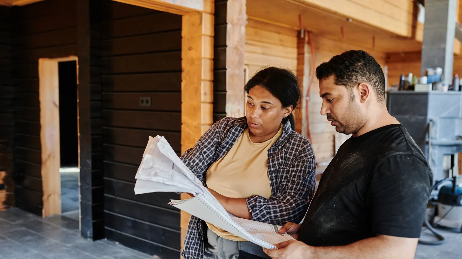 Two people standing outside a building reviewing printed plans together
