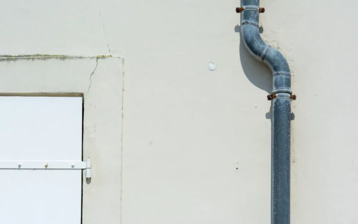 A pipe running down the exterior wall of a light-coloured building