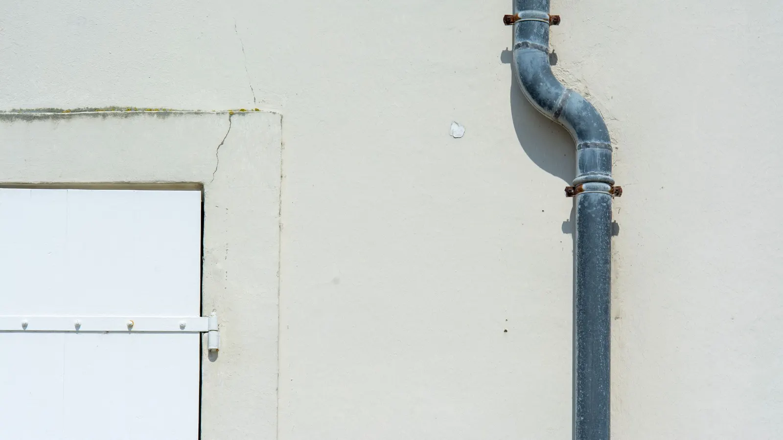 A pipe running down the exterior wall of a light-coloured building