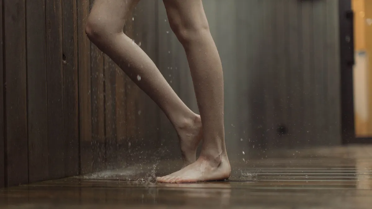 A person standing barefoot in shallow water on a floor
