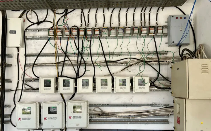 An electrical panel with wiring and meters mounted on a wall