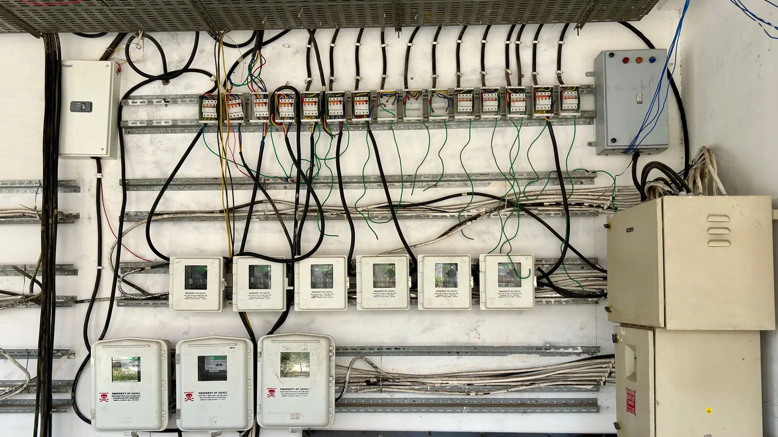 An electrical panel with wiring and meters mounted on a wall