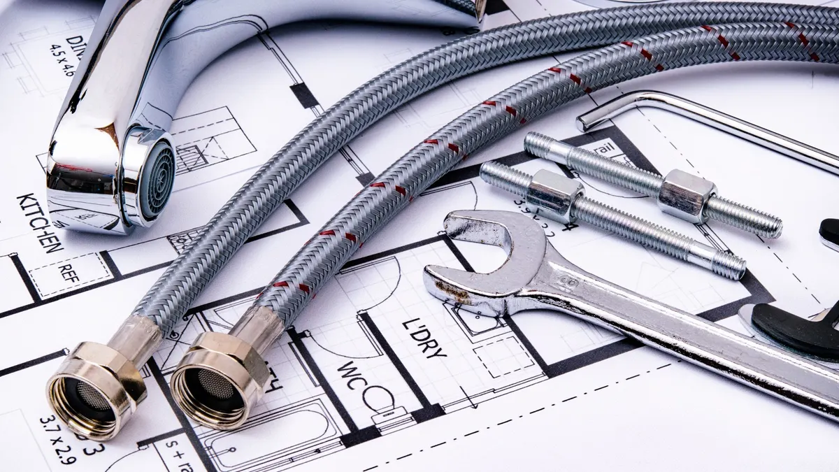 Flexible plumbing connectors and a wrench laid on a set of plans
