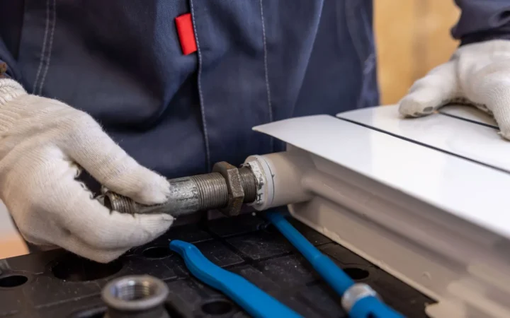 Gloved hands assembling pipe fittings on a workbench