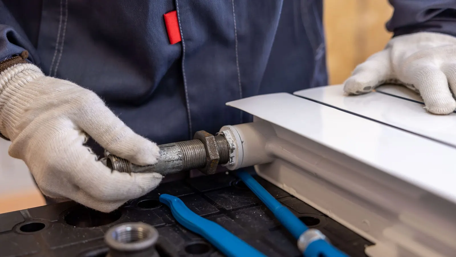 Gloved hands assembling pipe fittings on a workbench
