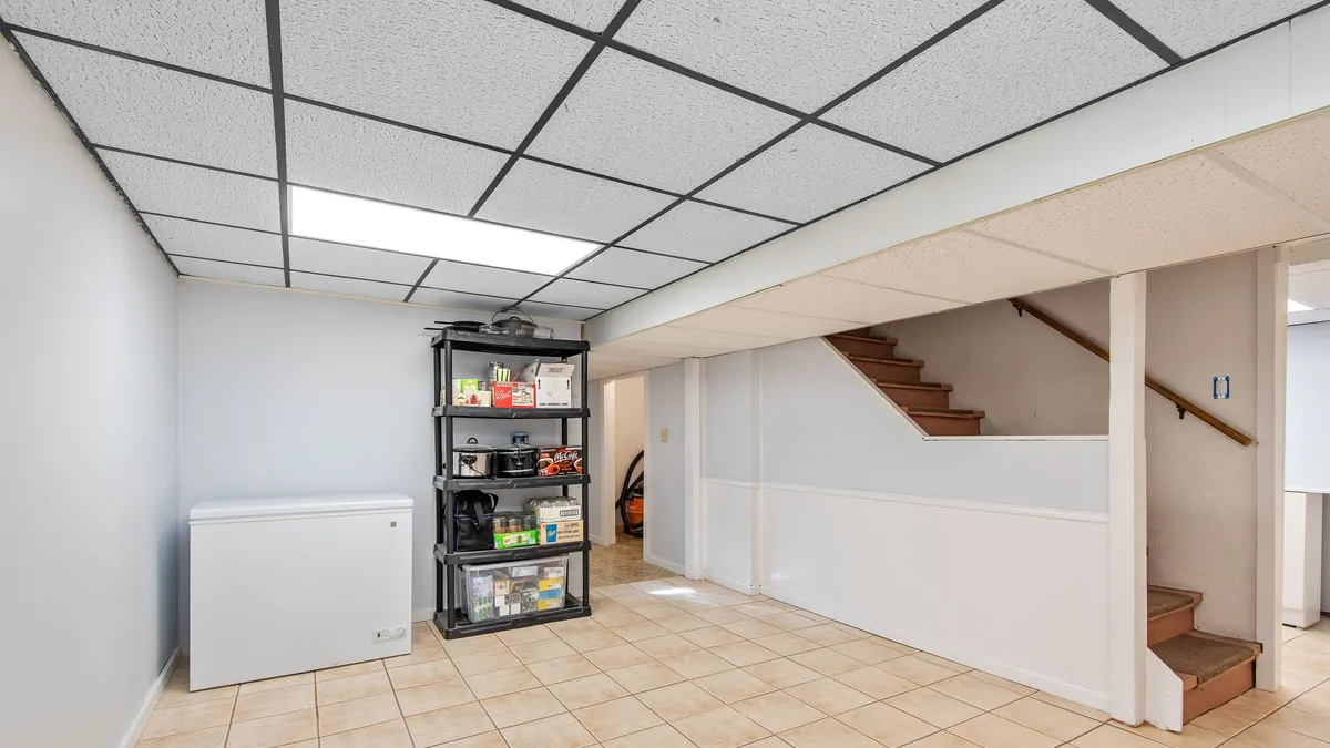 A tidy basement room with open shelving beneath a staircase