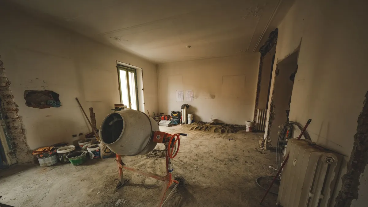 An unfinished basement with bare concrete walls, a rough floor and a machine in the corner