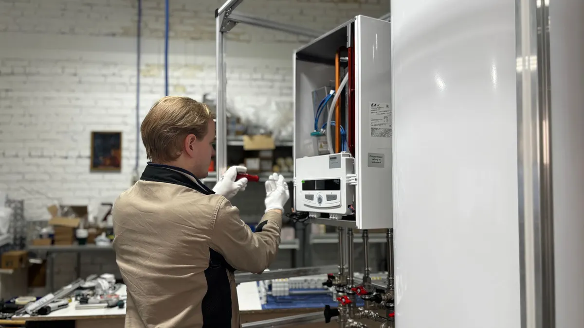 A technician working on a wall-mounted appliance in a utility room