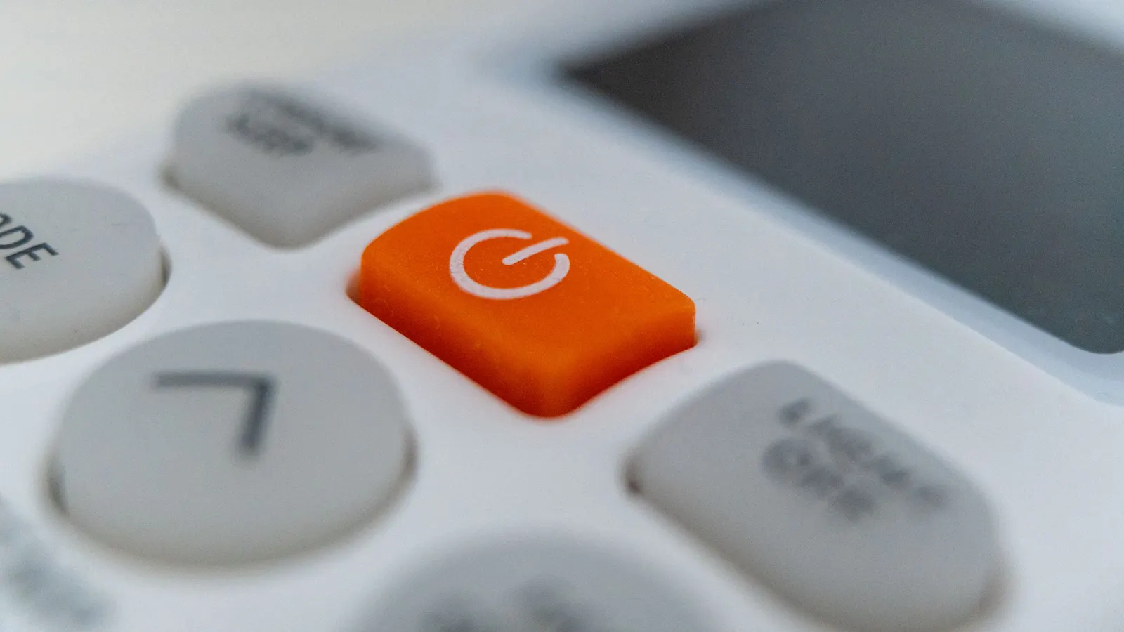 Close-up of an orange power button on an electronic remote control