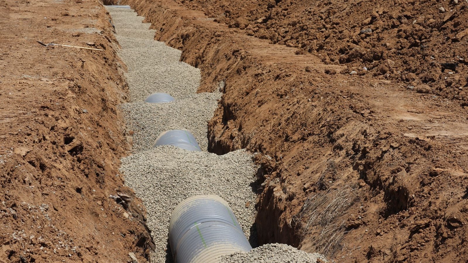 A trench containing perforated drainage pipe surrounded by gravel